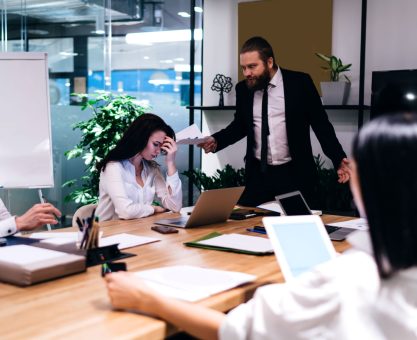 Jefe gritando a empleados en junta.